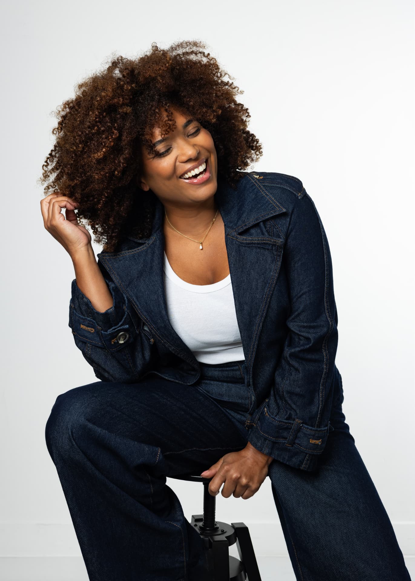 Robin-April zittend op een kruk in denim pak