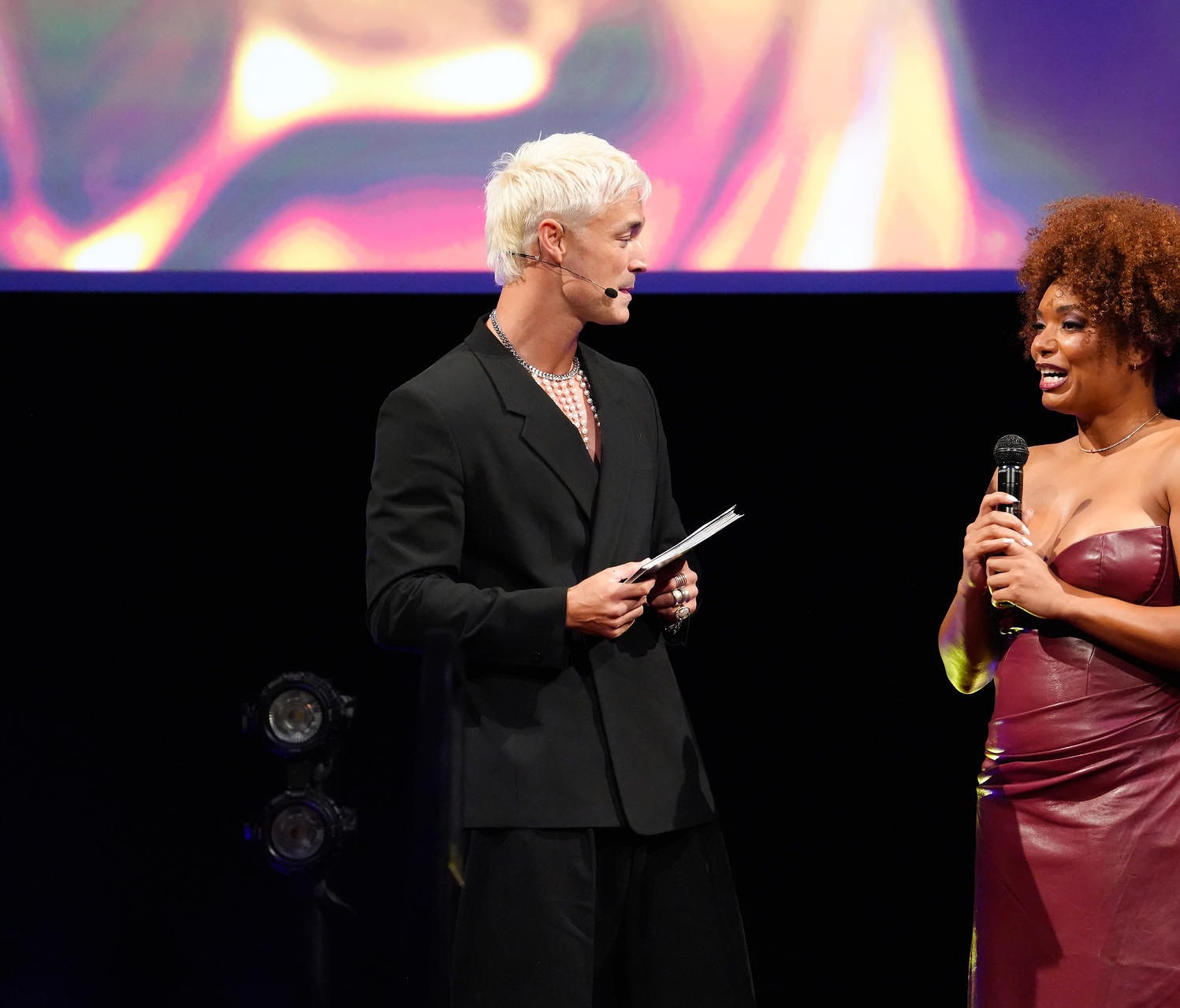 Robin-April lachend met microfoon op het podium